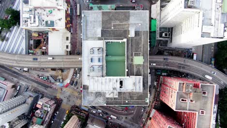 traffic passing through a car park building in downtown hong kong, with city mega buildings, aerial view