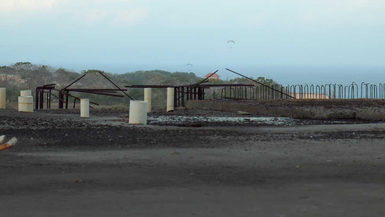 버려진 콘크리트 건설 폐허에서 광범위하게 찍은 사진은 해가 지는 동안 극적인 해안가를 보여줍니다.