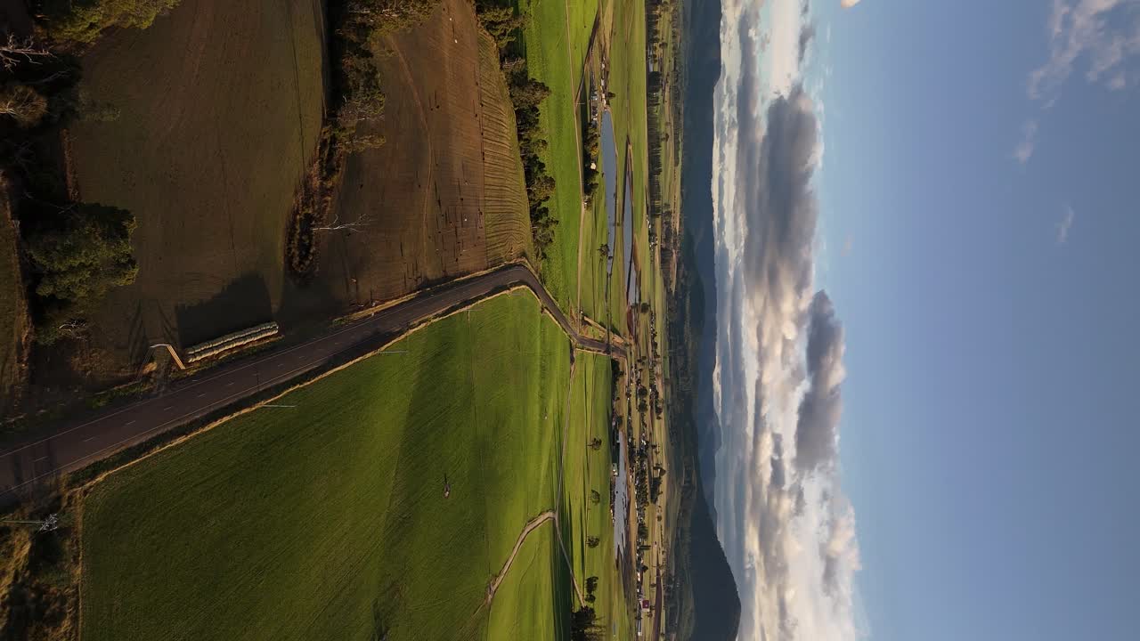 carretera rural de 4k60 en australia con campos verdes, tasmania al atardecer, vista de drones del paisaje rural