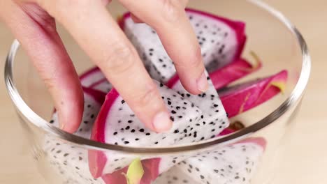 hand selecting dragon fruit pieces from bowl