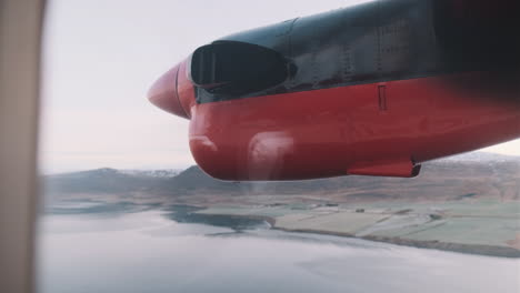 view out window of small plane propeller as plane flies over iceland fjord