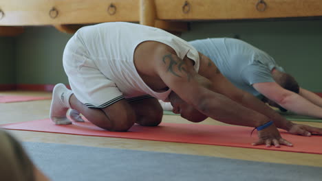 yoga class with tattooed man stretching