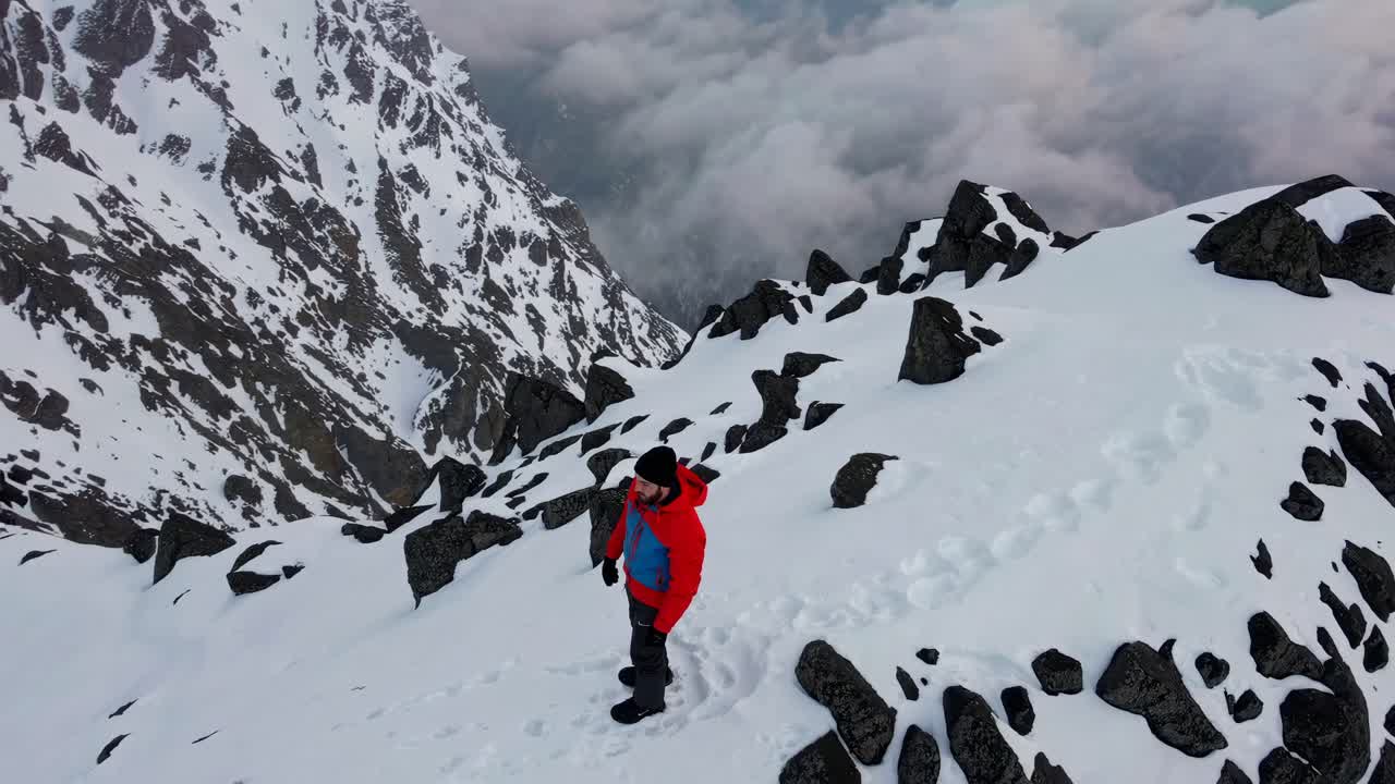 Man standing on snow-capped mountain summit