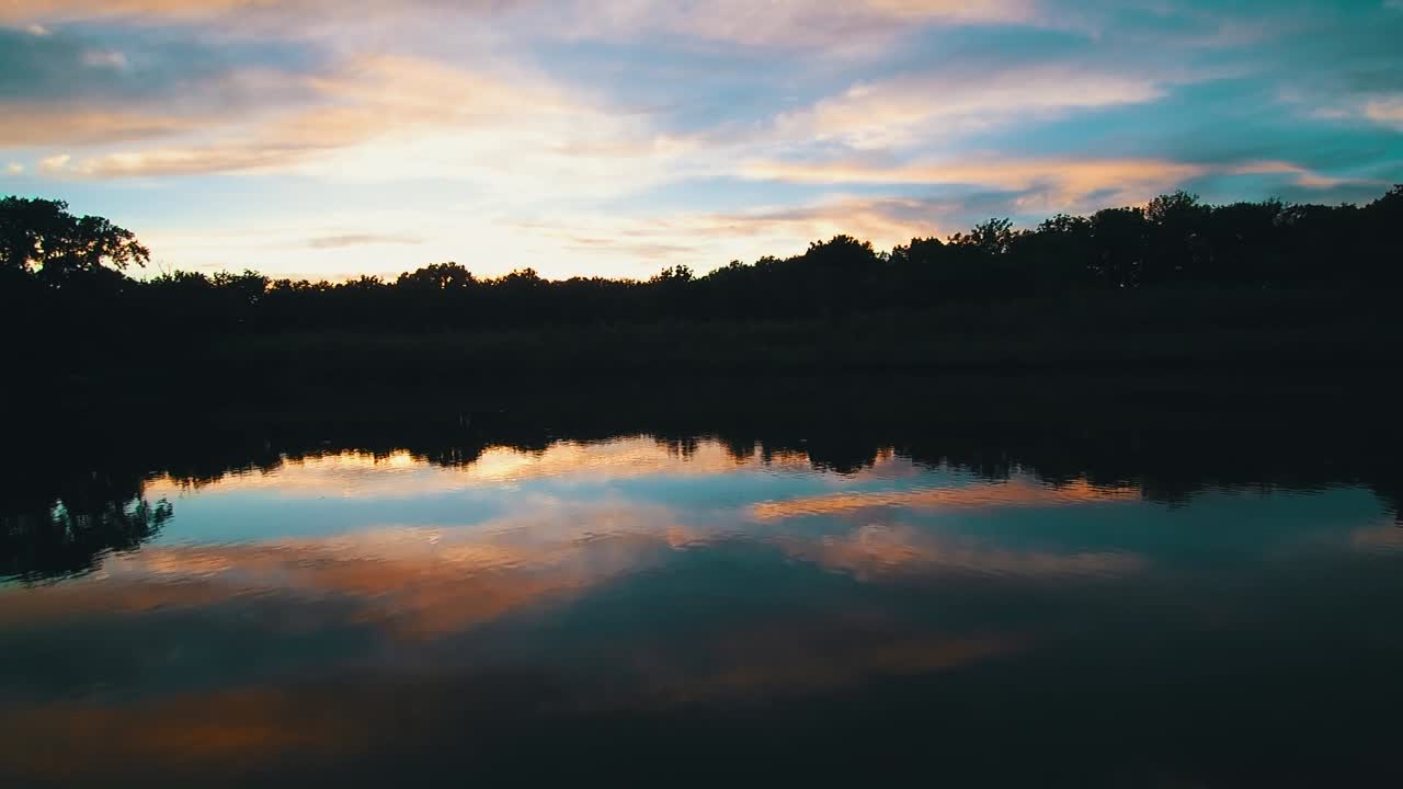 Aerial drone video of a glassy lake with cotton candy sky