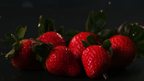 water drops on strawberries on black surface