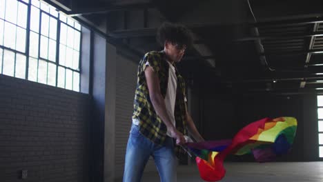 Portrait-of-african-american-man-waving-lgbt-flag-in-empty-parking-garage