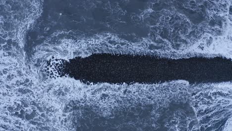 basalt rock barrier hit by powerful waves of the atlantic ocean - aerial straight down