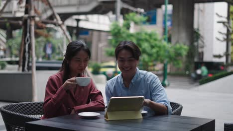 couple enjoying coffee and looking at tablet in an outdoor cafe