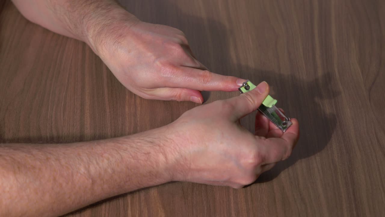 Man's Hands Clipping His Fingernails with a Clipper on a Table