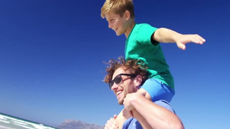 father carrying son on his shoulders at beach