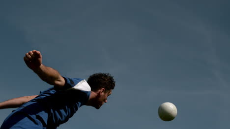 football player heading the ball under blue sky