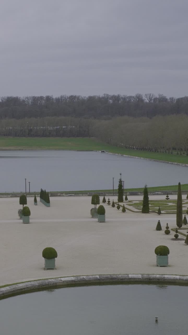 Peaceful gardens at Versailles with serene water and cloudy skies