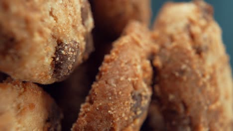 a vertical macro close up cinematic shot of a plate full of crispy chocolate chip cookies, on a rotating stand, studio lighting, super slow motion, 120 fps, full hd video