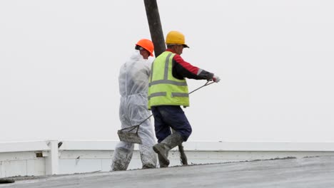 Dos-Hombres-Bombeando-Hormigón-En-Un-Tejado-En-Un-Sitio-De-Construcción-Industrial