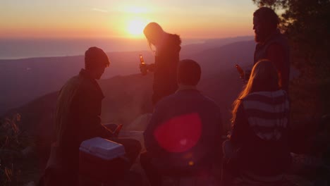 un grupo de amigos bebe cerveza en un camping mientras se pone el sol