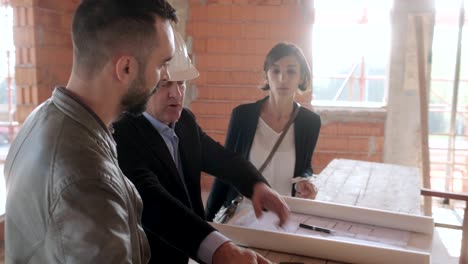 gerente mostrando el plan del proyecto a una pareja casada en su nueva casa