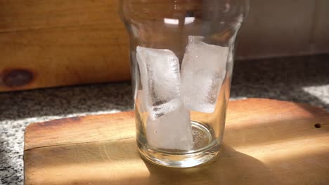 adding ice cubes in a glass to prepare a cocktail