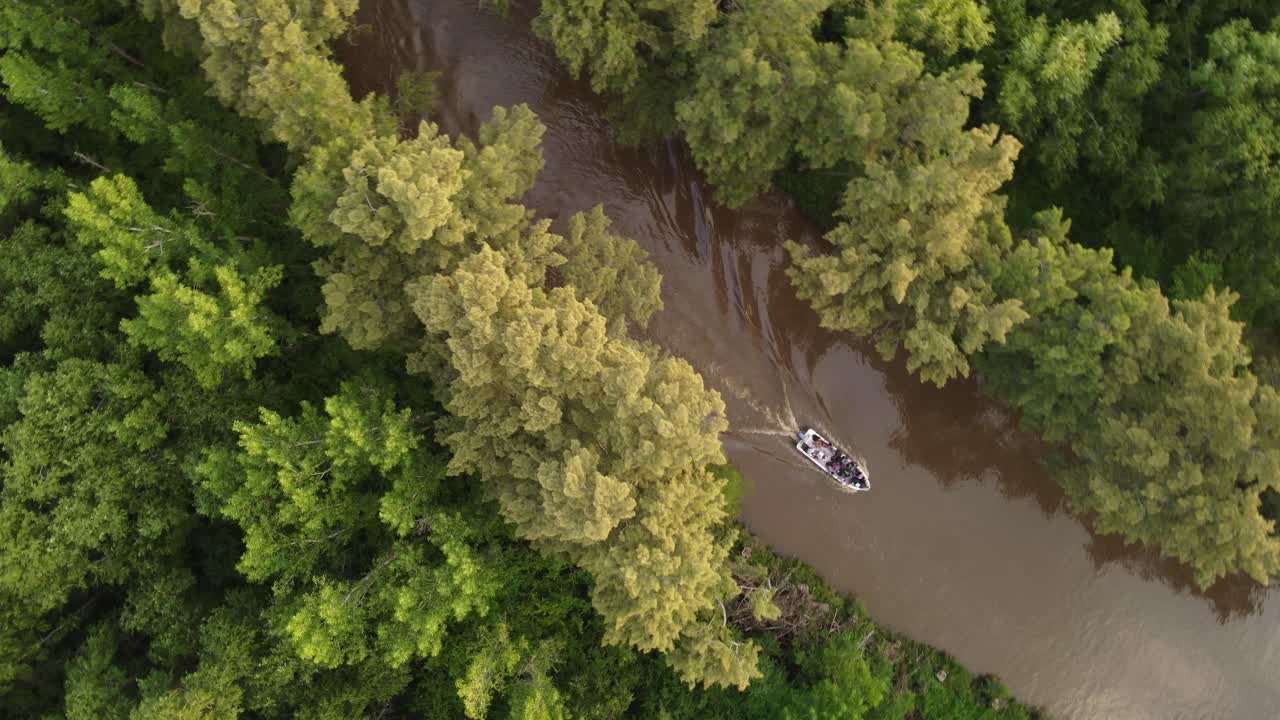 una foto aérea dinámica de arriba hacia abajo de un barco de pasajeros que cruza el río amazonas en el medio del bosque