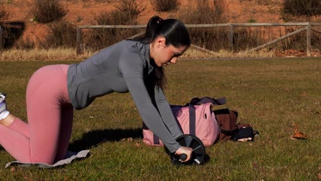 close-up of fit woman exercising with abdominal wheel outdoors on grass, 4k
