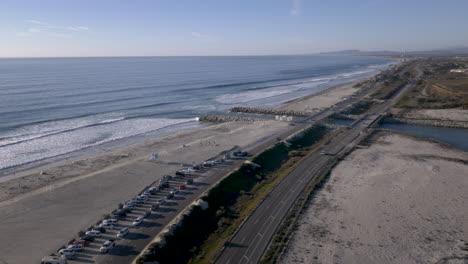 aerial view of a coastal beach, road, and parking lot