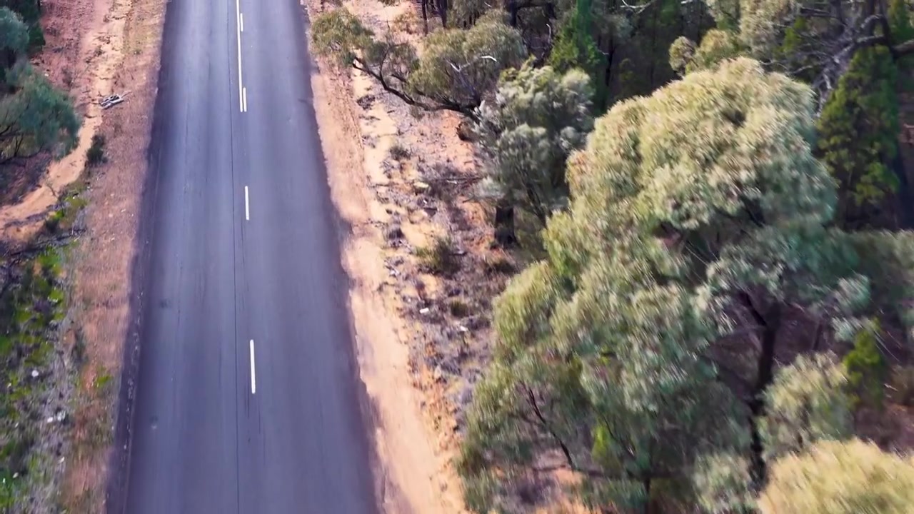 Luftfoto af tom asfaltvej gennem australsk busklandskab.