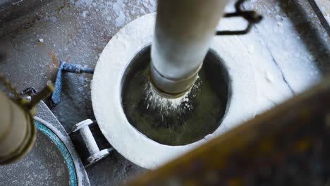 close up of filling kernel palm oil in a truck through metal pipe at factory, malaysia