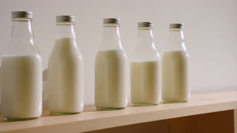five glass milk bottles on a wooden shelf