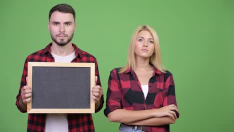 young couple holding blackboard and arms crossed together