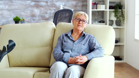 Zoom-in-shot-of-lonely-old-woman-sitting-on-couch