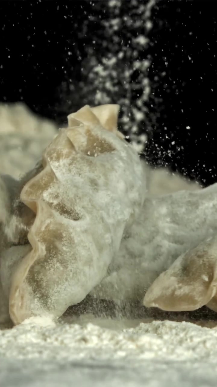 Slow Motion of Dumplings Falling into White Flour