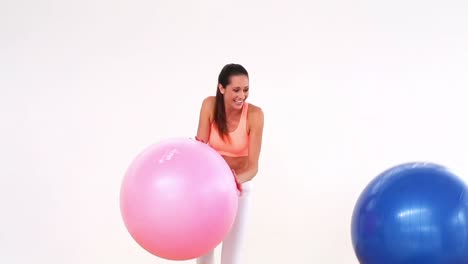 Fit-model-laughing-and-smiling-at-camera-with-exercise-balls