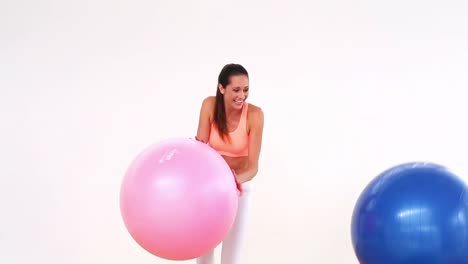 fit model laughing and smiling at camera with exercise balls