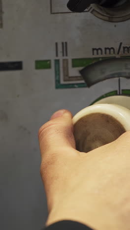 close-up of a hand operating a control dial on a machine