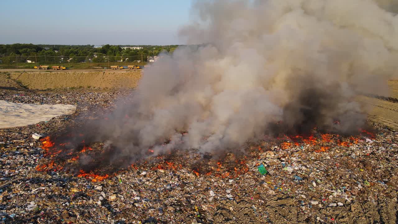 Trash fire burning at landfill with heavy smoke polluting environment