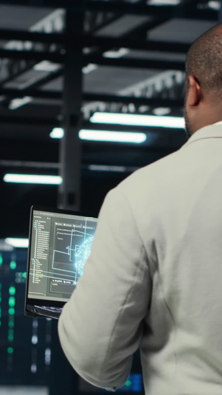 Vertical video Technician using laptop in data center, managing server virtualization