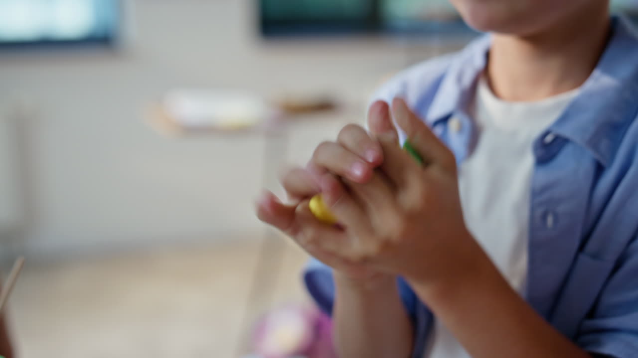 Primo piano di un bambino che modella plastilina colorata durante un'attività in classe. Creatività degli studenti
