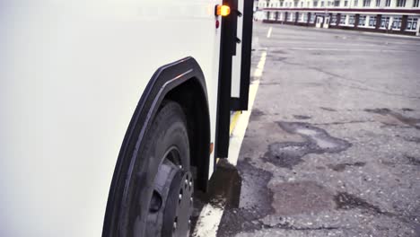 primer plano de la rueda trasera y el lado de un autobús blanco