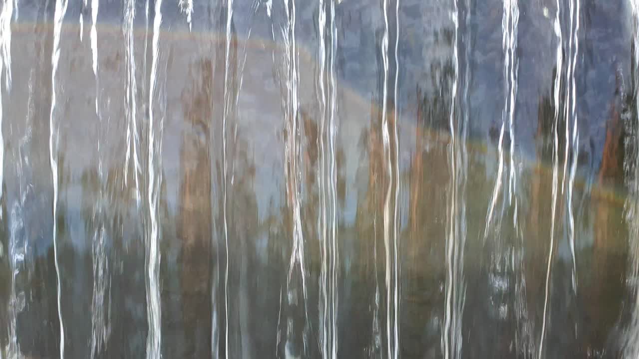 Fresh mountain water flowing gently over a dam wall, close up and abstract