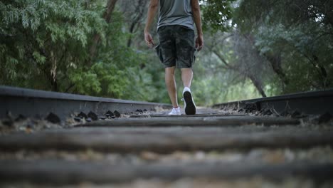 slow motion shot of a lonely man walking on abandoned train tracks