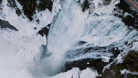 huge waterfall flowing around frozen ice and snow frozen river in winter