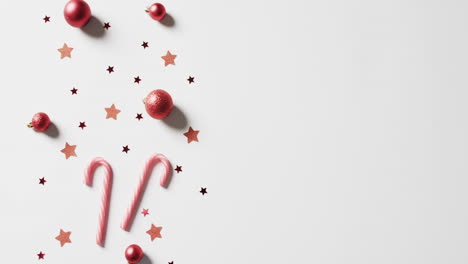 video of baubles, candy canes and stars christmas decorations with copy space on white background