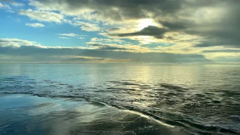 Malerischer-Blick-Auf-Das-Meer-In-Zeitlupe-Bei-Sonnenlicht,-Das-Sich-Tagsüber-Hinter-Der-Wolkenlandschaft-Versteckt---Keine-Menschen-Am-Strand-Mit-Ruhigem-Wasser