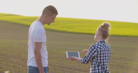 couple on farm talking in field of green plants 1