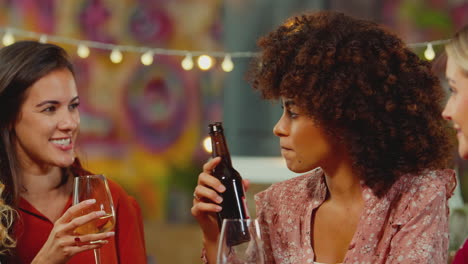 group of multi-cultural female friends sitting at table drinking and enjoying girls night out