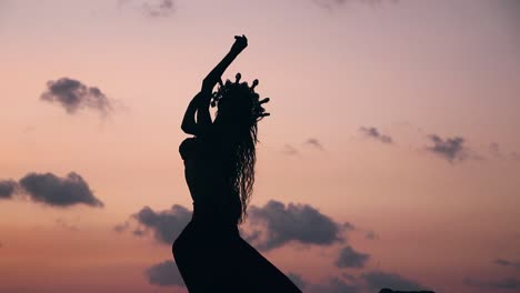 close up of sexy, elegant and erotic arabian woman performing belly dance on the beach during golden hour. silhouette