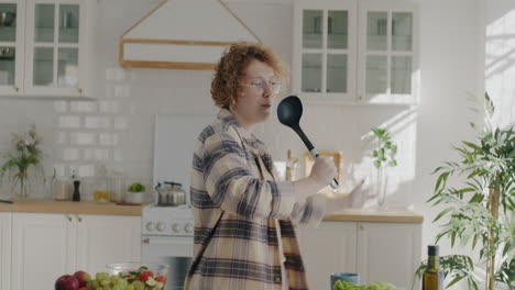 woman singing and dancing in kitchen while preparing salad