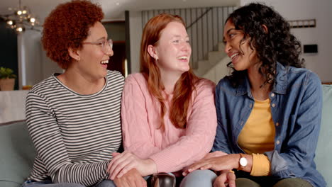 laughing and bonding, diverse female friends sitting together on couch indoors