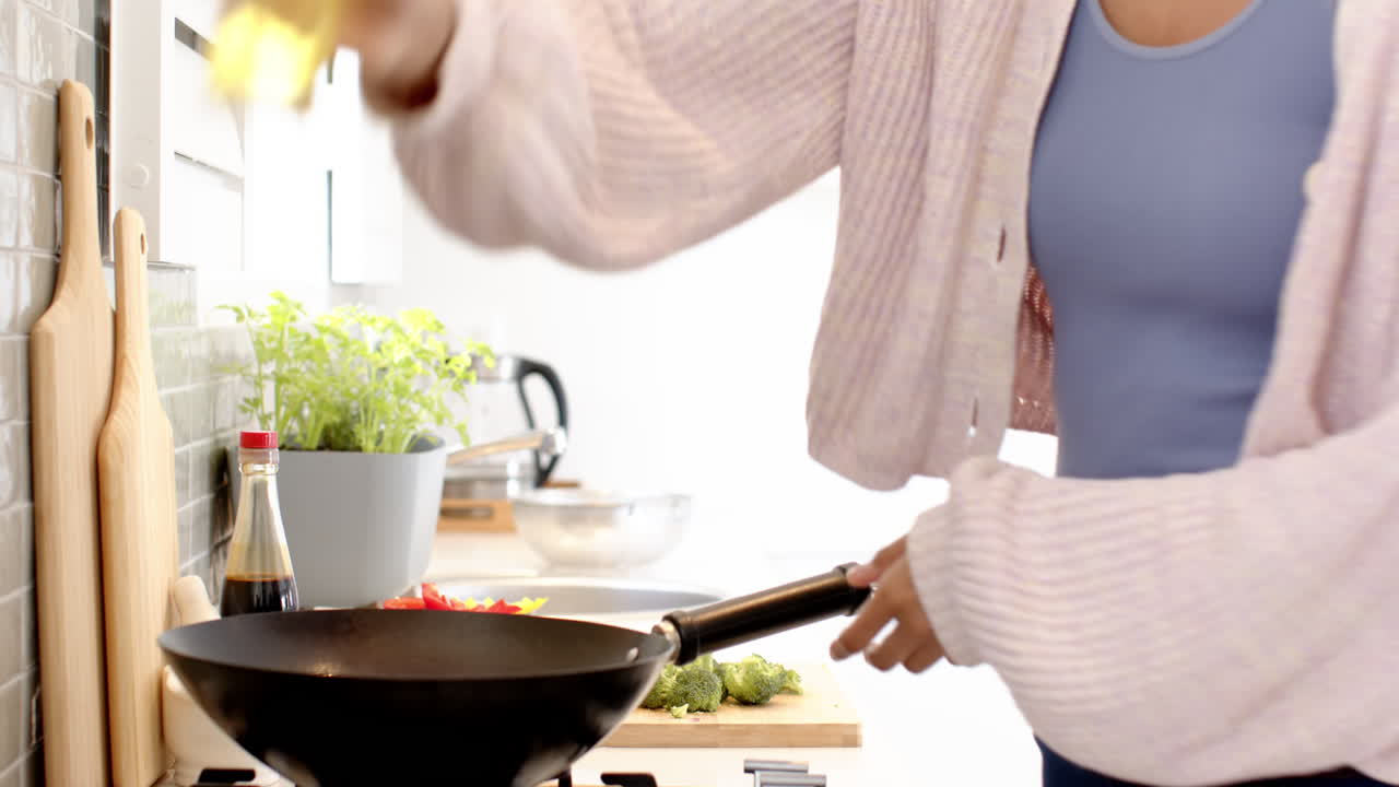 Cooking stir-fry, woman tossing vegetables in wok at home kitchen