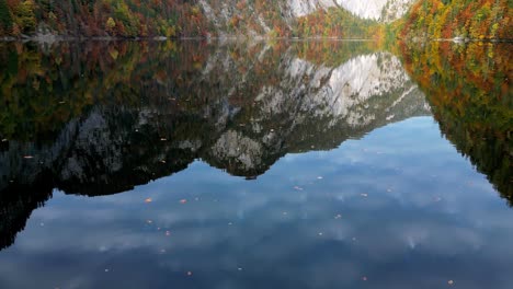 Una-Toma-Fija-Y-Amplia-De-Un-Colorido-Paisaje-Otoñal-Con-Un-Lago-Tranquilo-Que-Refleja-El-Vibrante-Follaje-De-Las-Montañas-Y-árboles-Circundantes