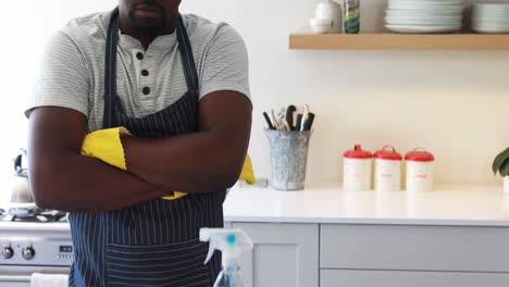 hombre confiado de pie con los brazos cruzados en la cocina